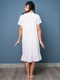 Girl wearing a white dress with a subtle pattern against a blue wall.