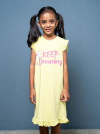 Young girl wearing a yellow dress with 'Keep Dreaming' text against a blue background