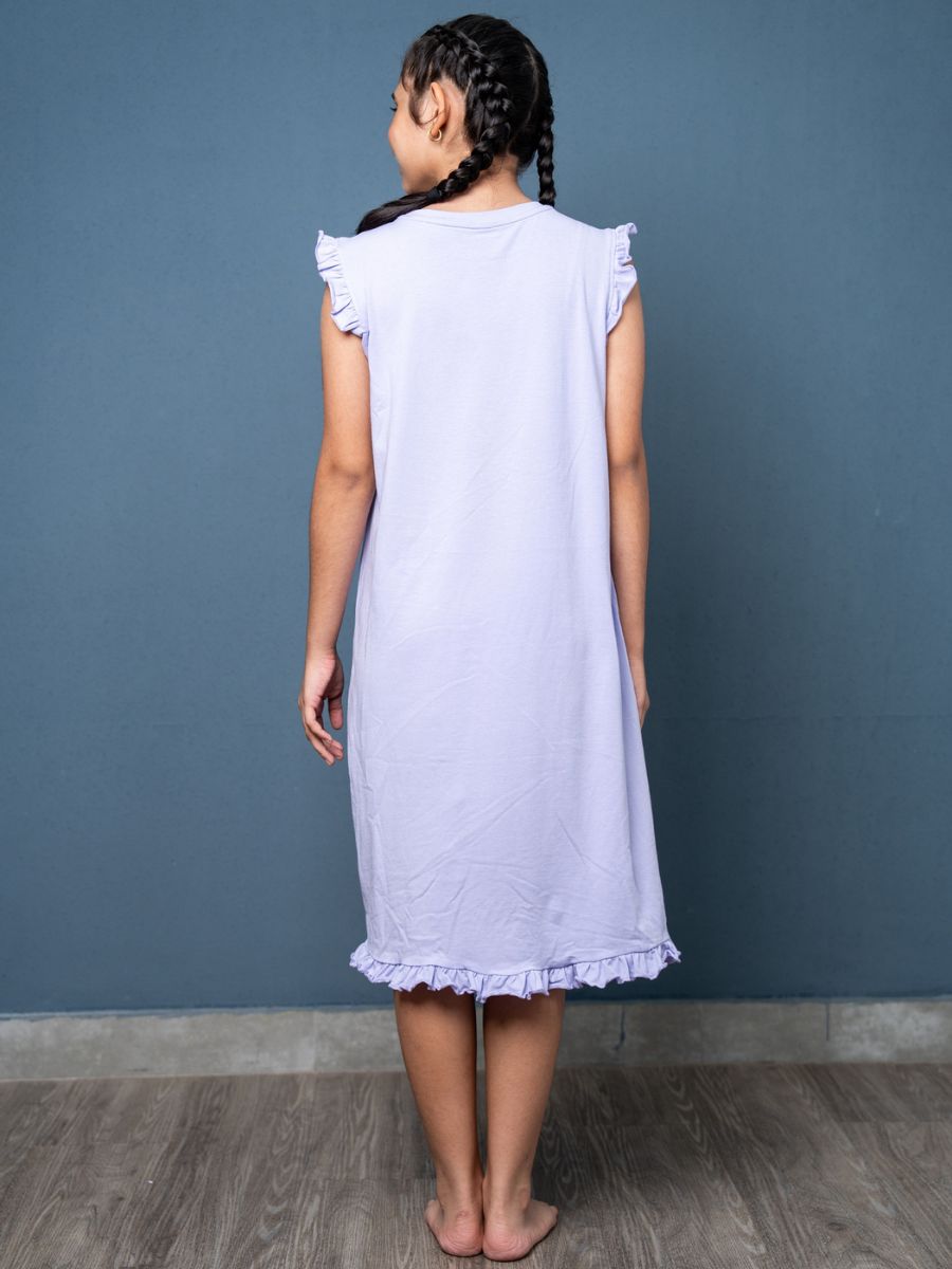 Young girl wearing a light purple dress against a blue wall.