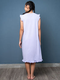 Young girl wearing a light purple dress against a blue wall.