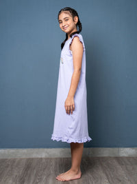 Young girl wearing a light purple dress against a blue wall