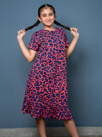 Young girl wearing a pink and blue patterned dress against a gray background