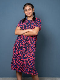 Young girl wearing a pink and blue patterned dress against a blue background