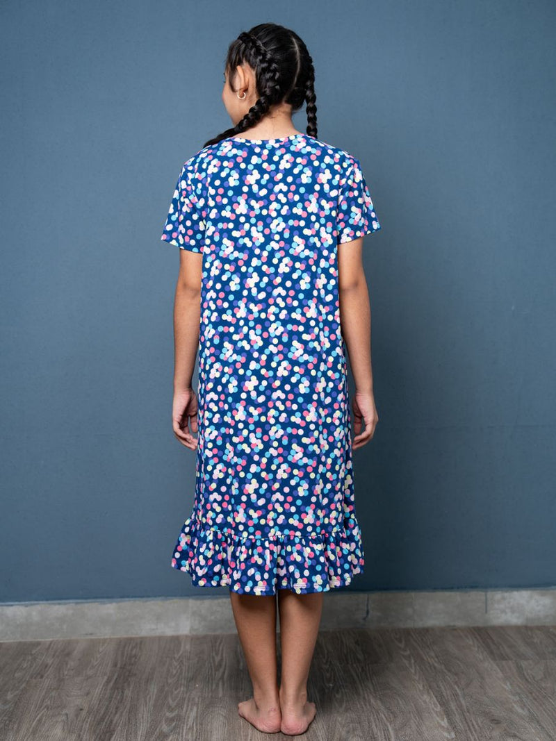 Girl wearing a blue floral dress against a gray wall