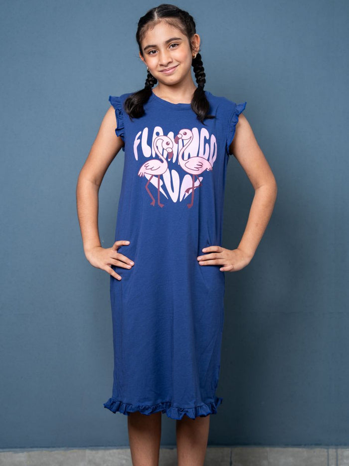 Girl wearing a blue dress with flamingo design against a gray background