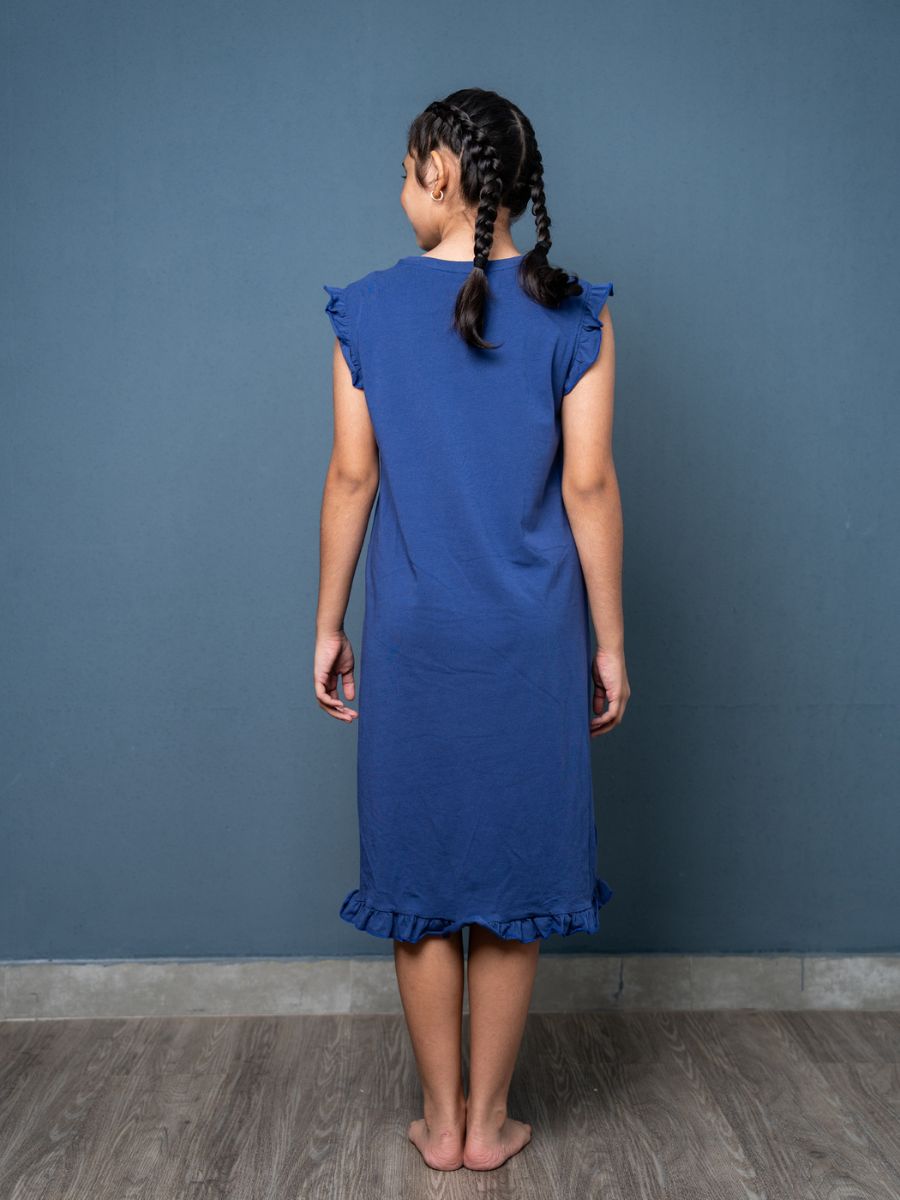 Young girl wearing a blue dress against a gray wall