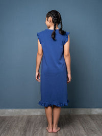 Young girl wearing a blue dress against a gray wall