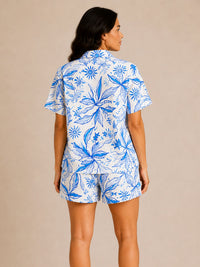 Woman wearing a blue and white floral pajama set on a beige background