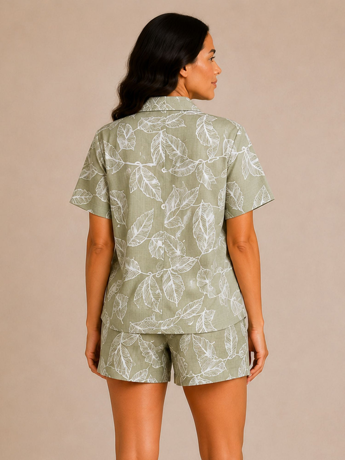 Woman wearing a green leaf-patterned shirt and shorts set against a beige background