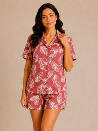 Woman wearing a red and white leaf-patterned pajama set against a beige background