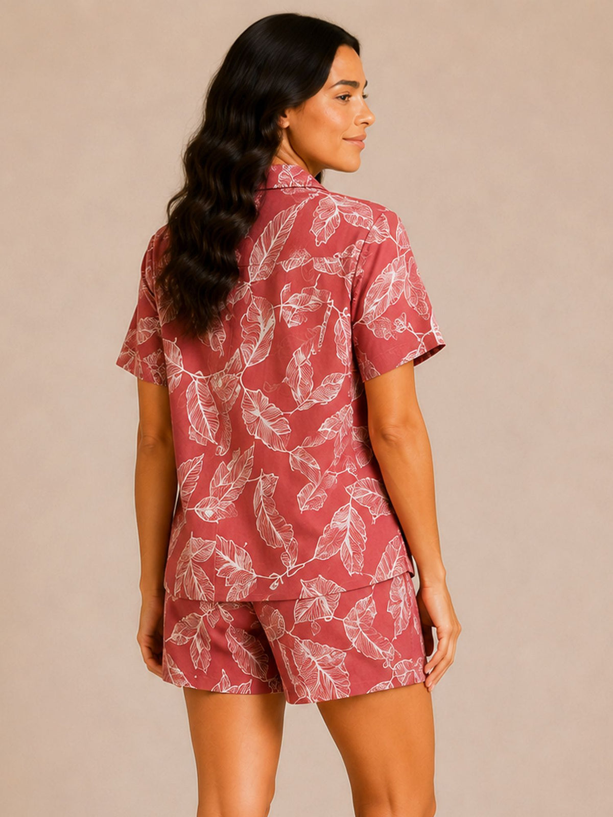 Woman wearing a red and white leaf-patterned shirt and shorts set on a beige background