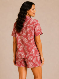 Woman wearing a red and white leaf-patterned shirt and shorts set on a beige background