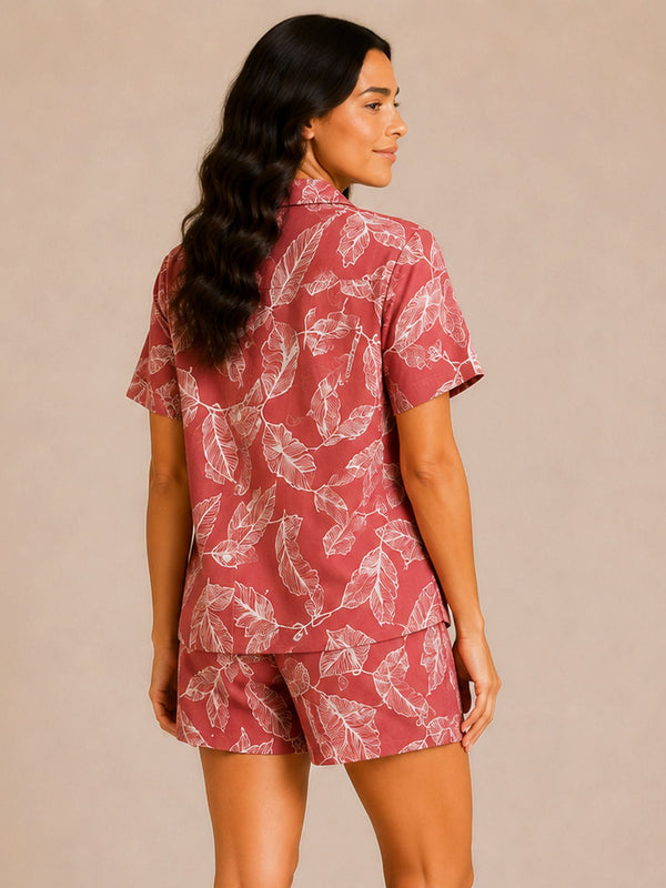 Woman wearing a red and white leaf-patterned shirt and shorts set on a beige background