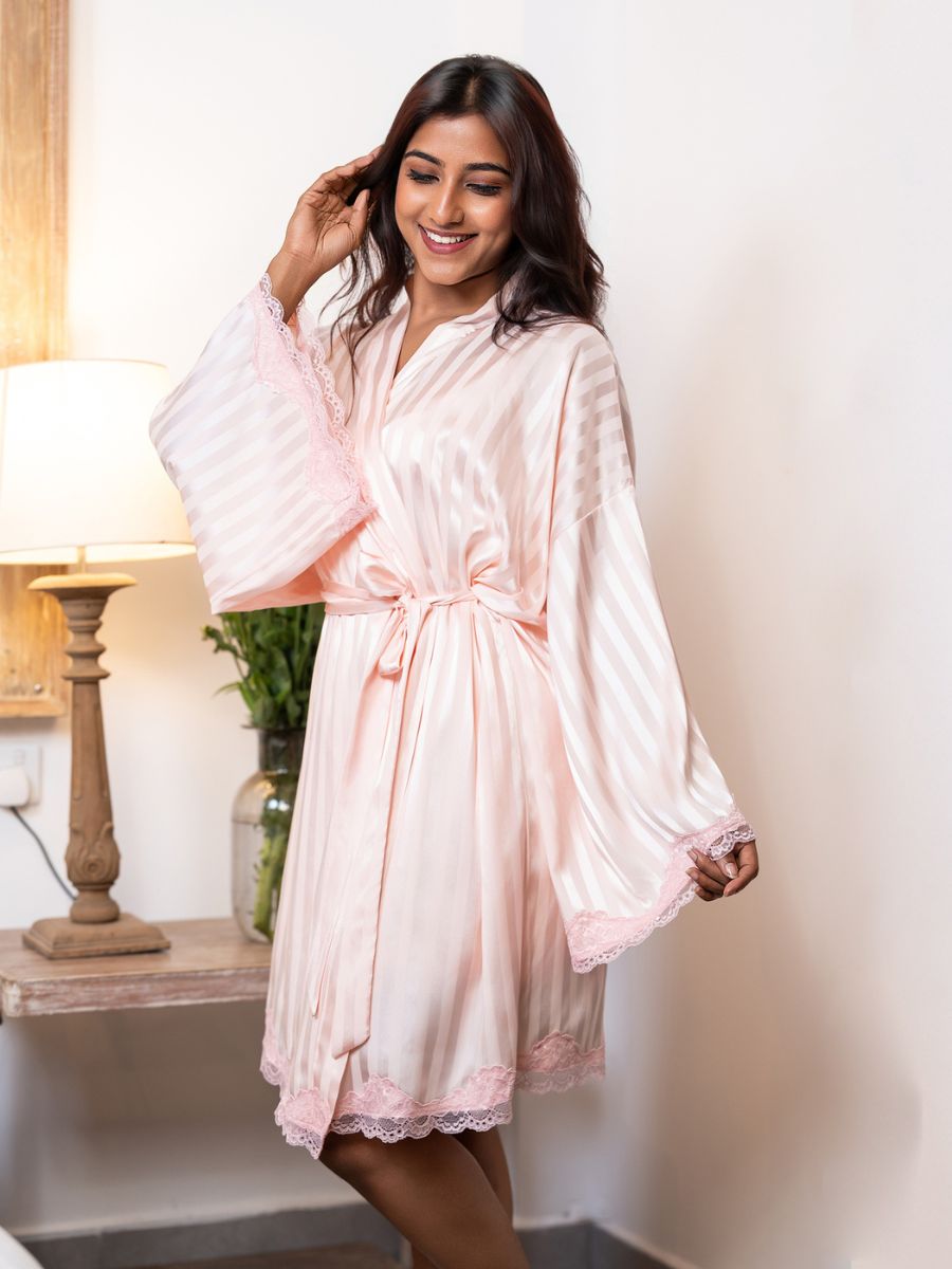 Woman wearing a light pink satin robe in a cozy room.