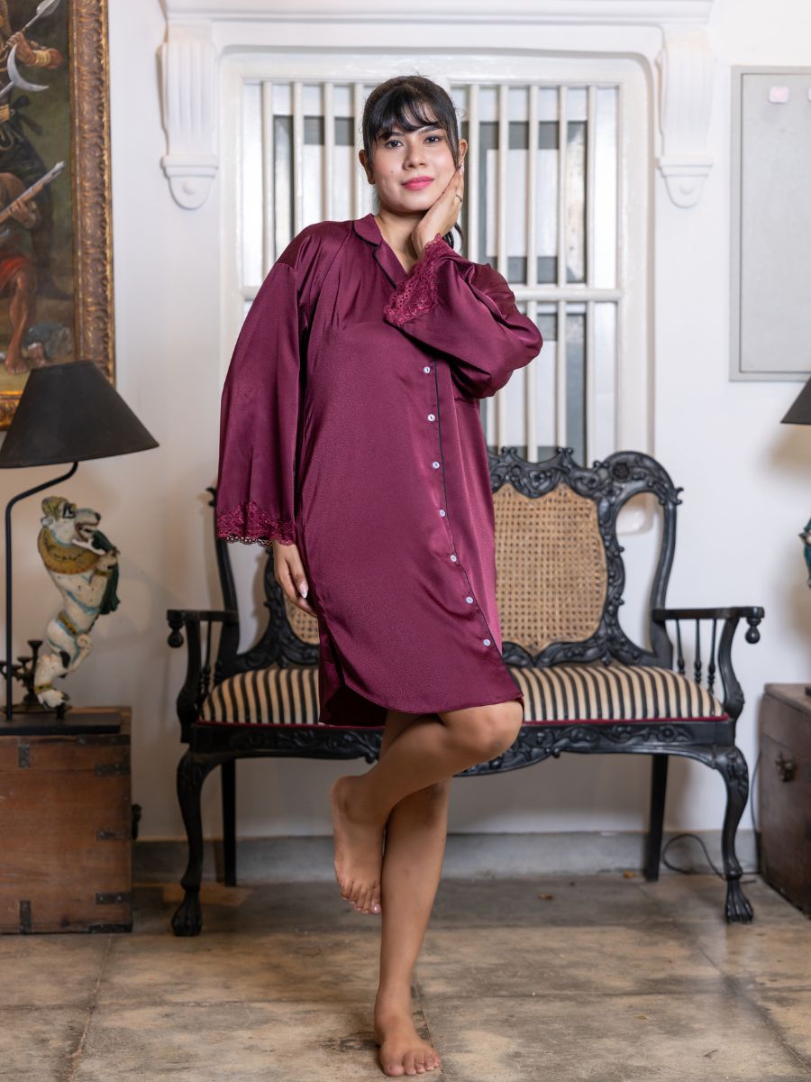 Woman in a burgundy dress standing in an elegant room with a fireplace and decorative items.