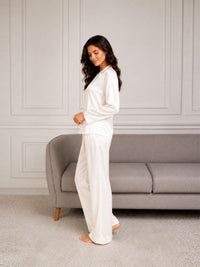 Woman in white pajamas standing in a room with a gray sofa.