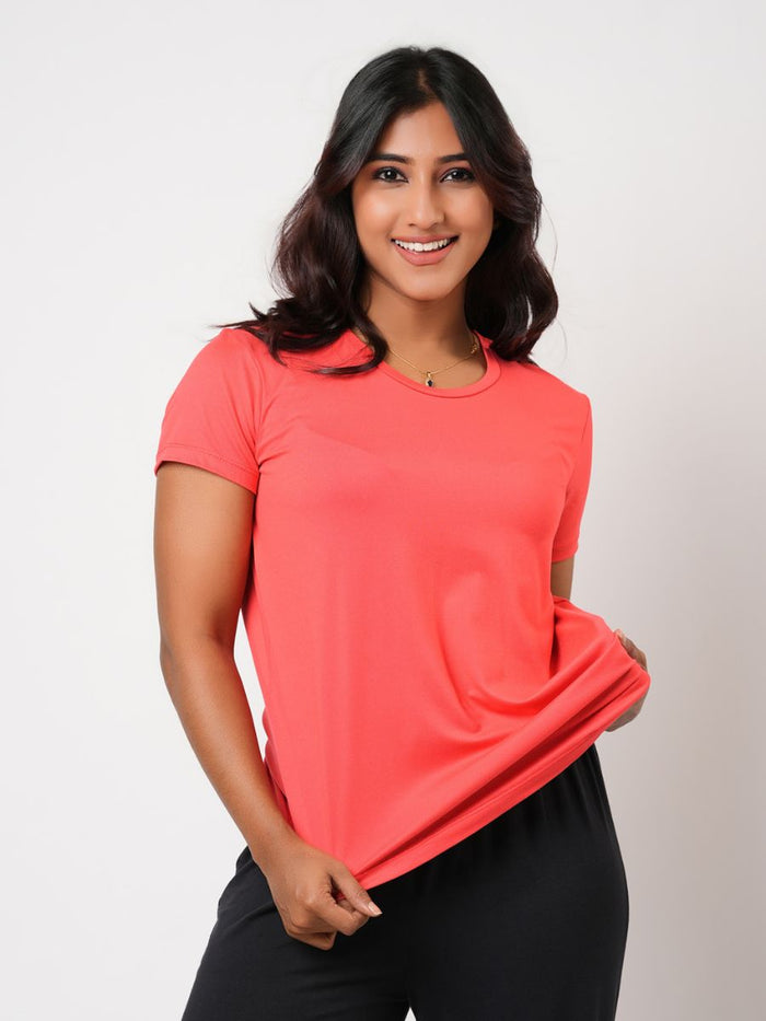 Woman wearing a coral pink t-shirt against a plain background