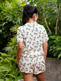 Person wearing a floral pajama set with greenery in the background