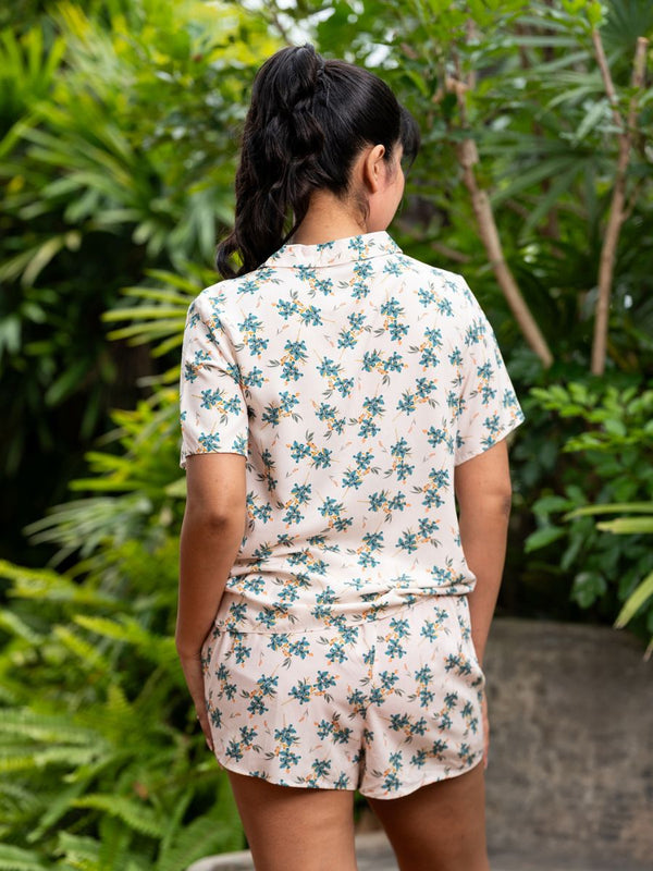 Person wearing a floral pajama set with greenery in the background
