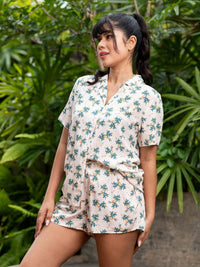 Woman wearing a floral romper standing in front of green foliage