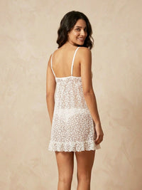 Woman wearing a white lace nightgown against a beige background