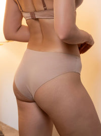 Person wearing beige underwear with a blurred background